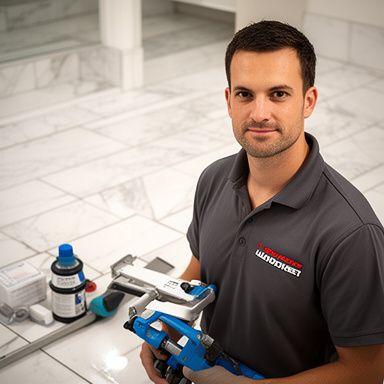 Lead technician standing beside a freshly restored bathroom floor with grout tools in hand
